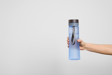 Photo of Woman holding bottle of water on light grey background, closeup. Space for text