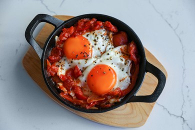 Photo of Tasty Shakshouka served in pan on white marble table, top view