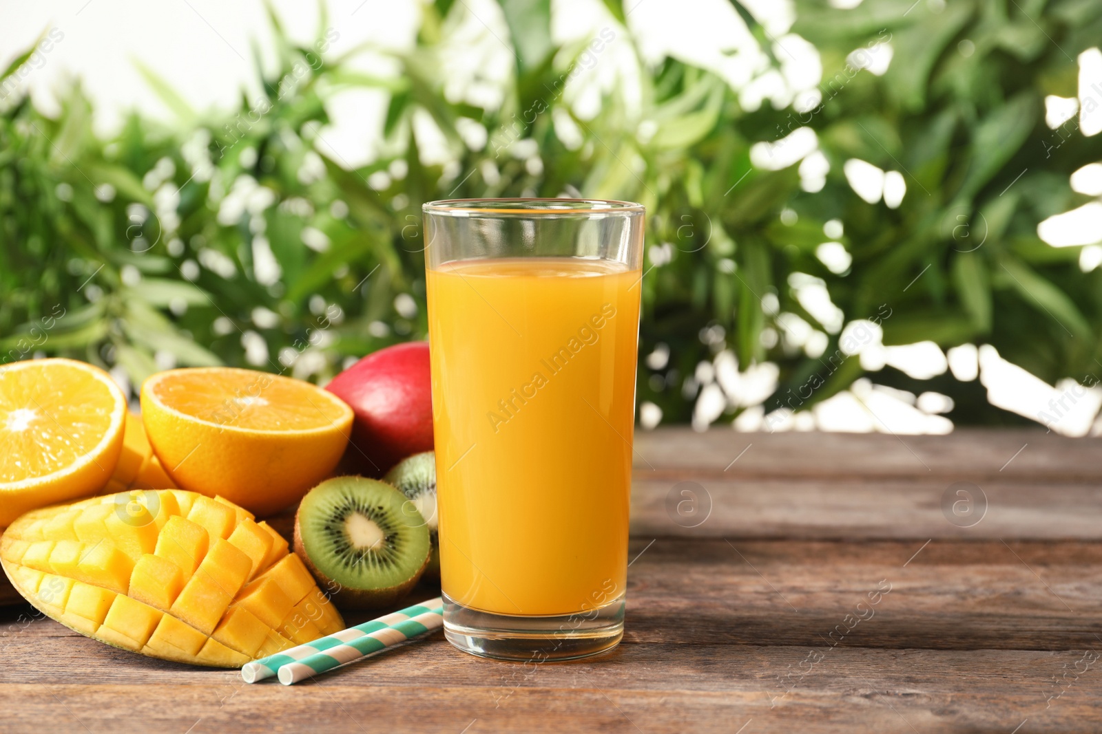 Photo of Tasty tropical drink with mango and fresh fruits on wooden table against blurred background. Space for text