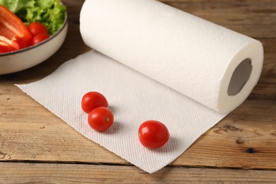 Photo of Fresh tomatoes and roll of paper towels on wooden table