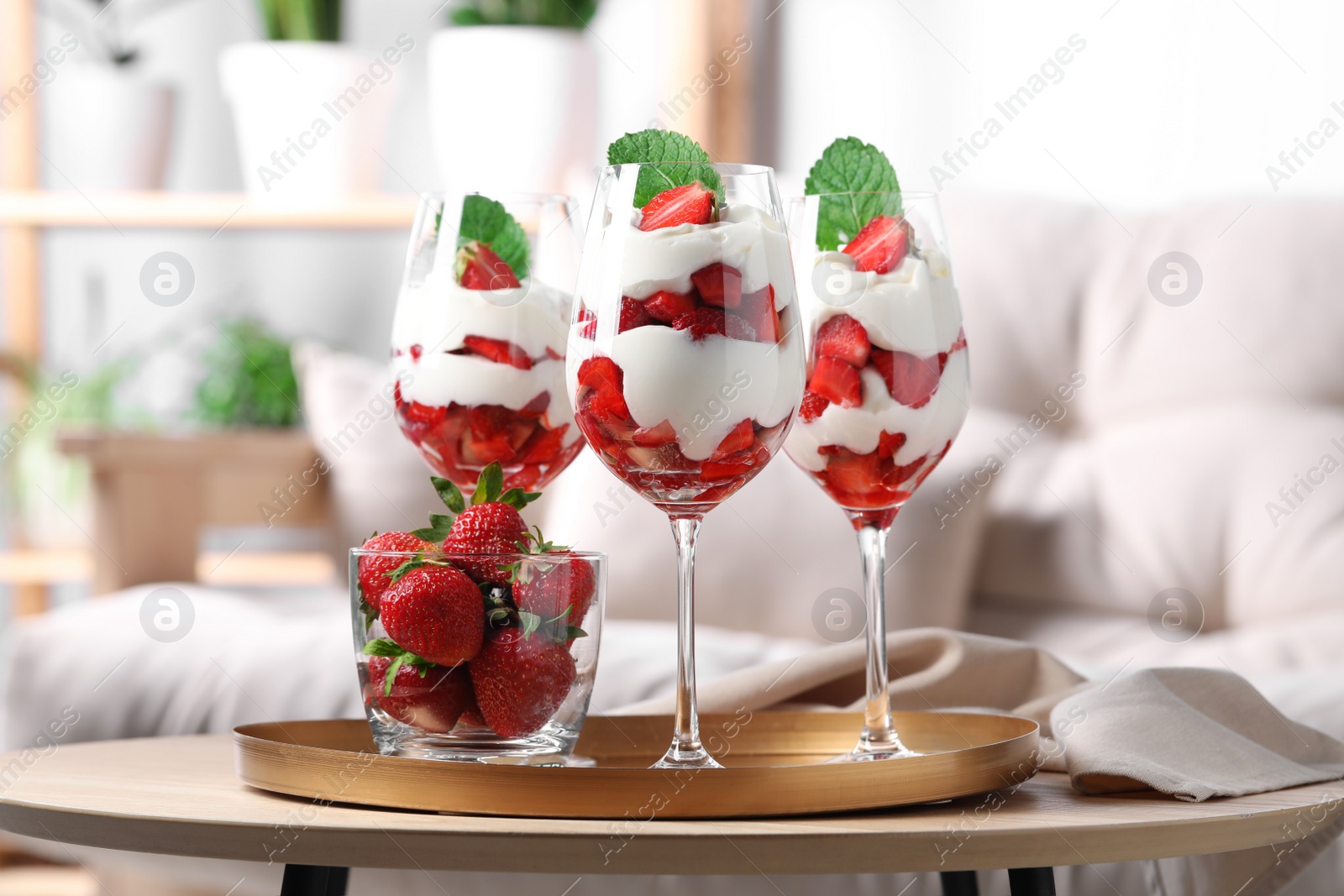 Photo of Delicious strawberries with whipped cream on wooden table indoors