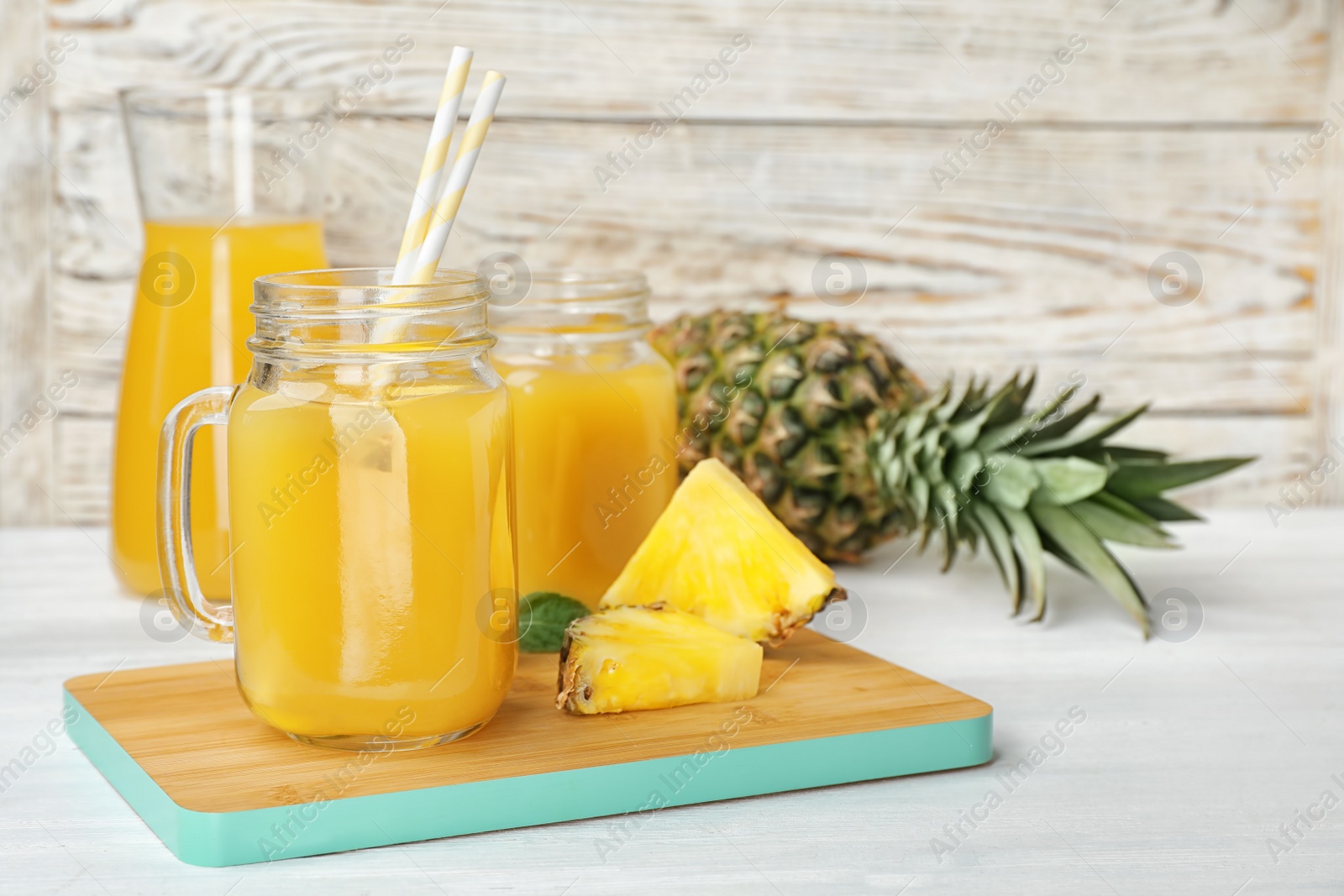 Photo of Mason jars with delicious pineapple juice on table