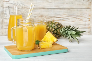 Photo of Mason jars with delicious pineapple juice on table