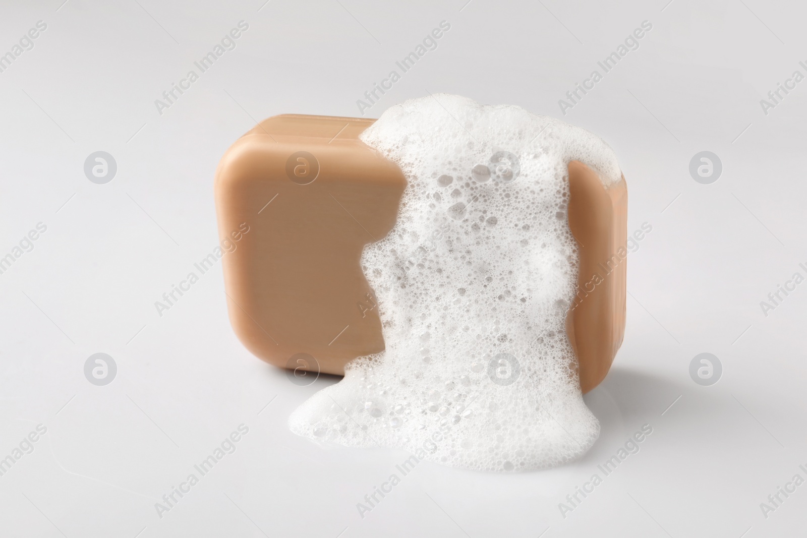 Photo of Soap with fluffy foam on white background