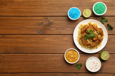 Photo of Traditional Indian food and color powders on wooden table, flat lay with space for text. Holi festival celebration