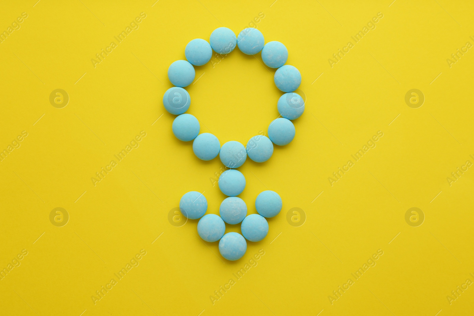 Photo of Male sign made of blue pills on yellow background, flat lay. Potency problems