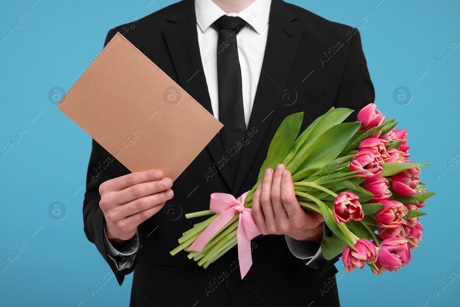 Photo of Man with beautiful bouquet and greeting card on light blue background, closeup