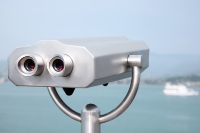 Photo of Metal tower viewer installed near sea. Mounted binoculars