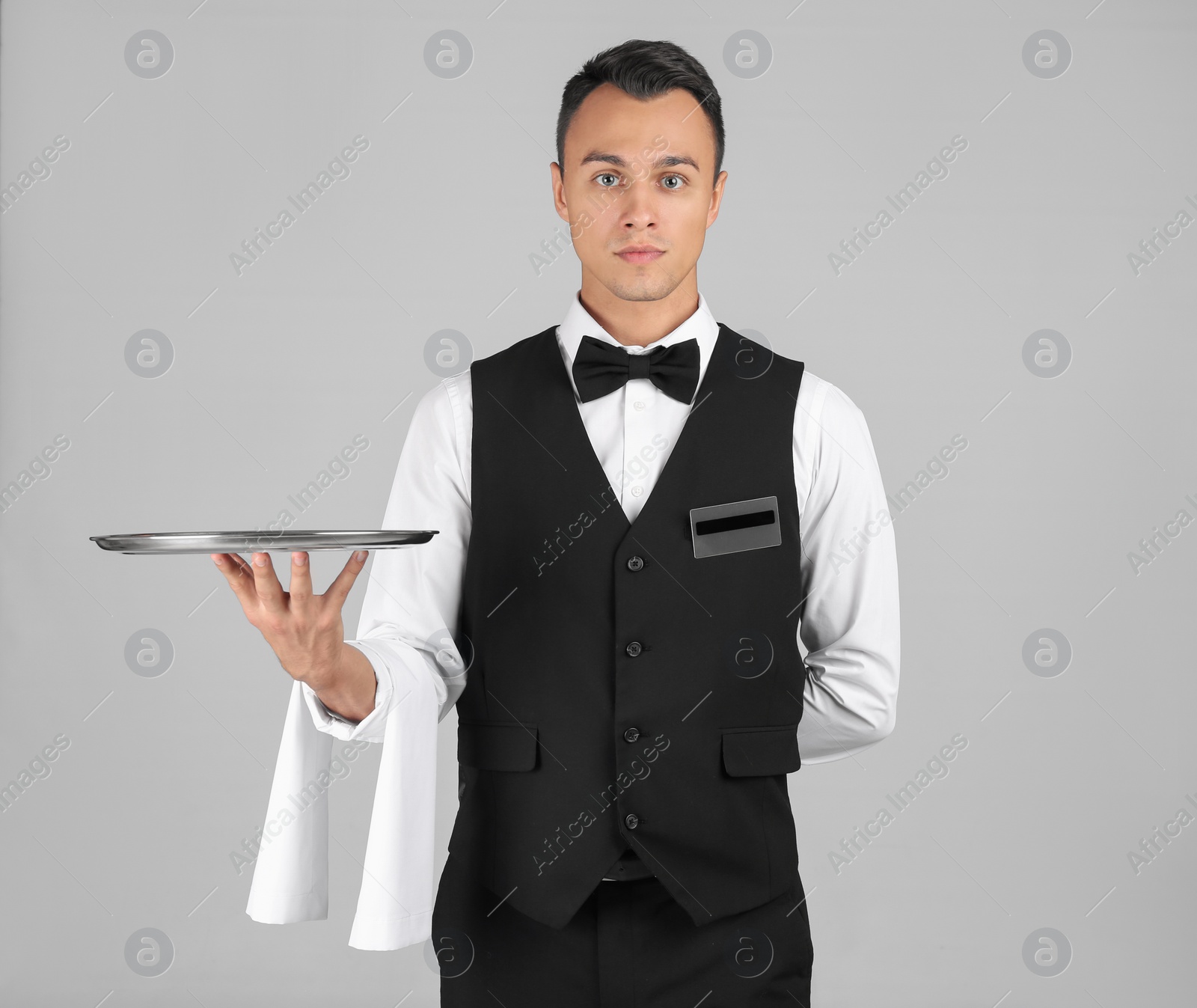 Photo of Waiter holding metal tray on grey background