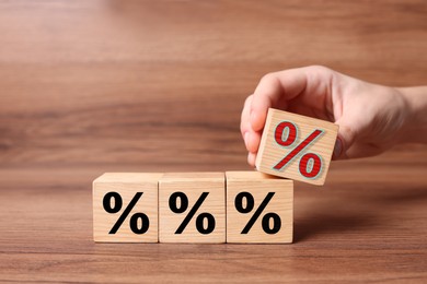 Best mortgage interest rate. Woman holding cube with red percent sign over wooden table, closeup