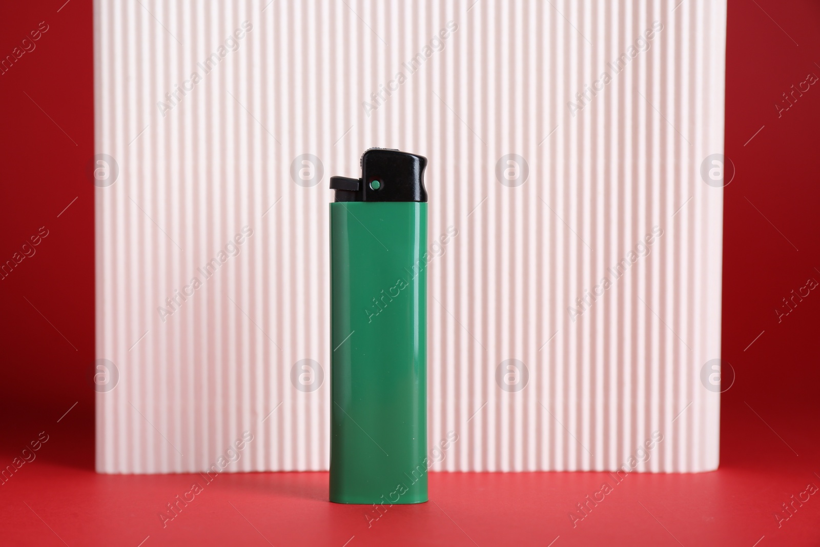 Photo of Stylish small pocket lighter and white corrugated fiberboard on red background