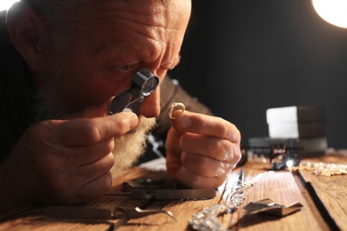 Photo of Male jeweler evaluating diamond ring in workshop