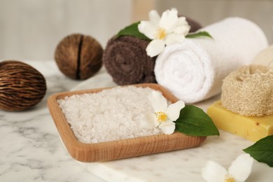 Composition with beautiful jasmine flowers and sea salt on white marble table