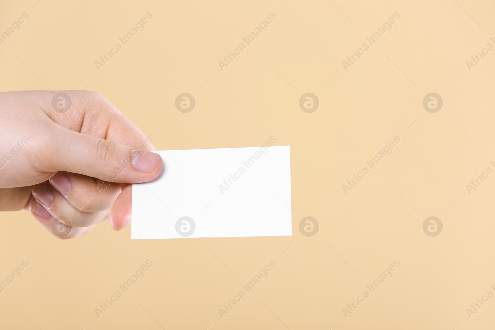 Photo of Man holding paper card on pale orange background, closeup. Mockup for design