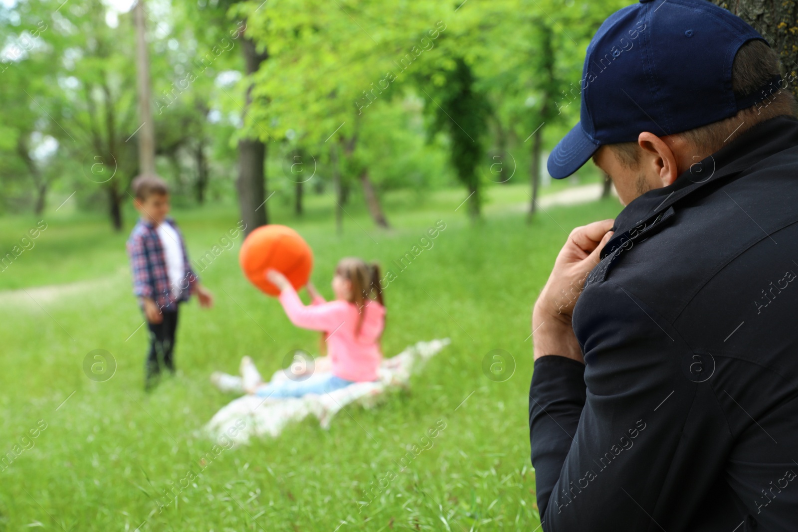 Photo of Suspicious adult man spying on kids at park. Child in danger