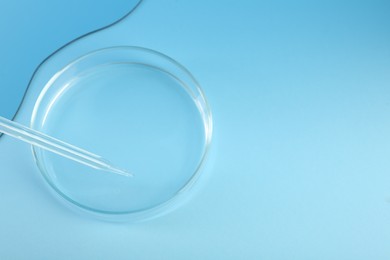 Photo of Empty petri dish and pipette on light blue background. Space for text