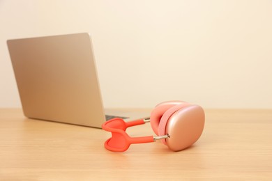 Photo of Modern headphones and laptop on wooden table. Space for text