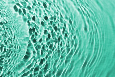 Rippled surface of clear water on green background, closeup