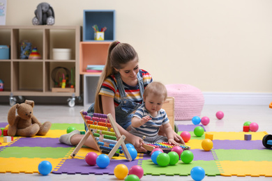 Teen nanny and cute little baby playing with xylophone at home