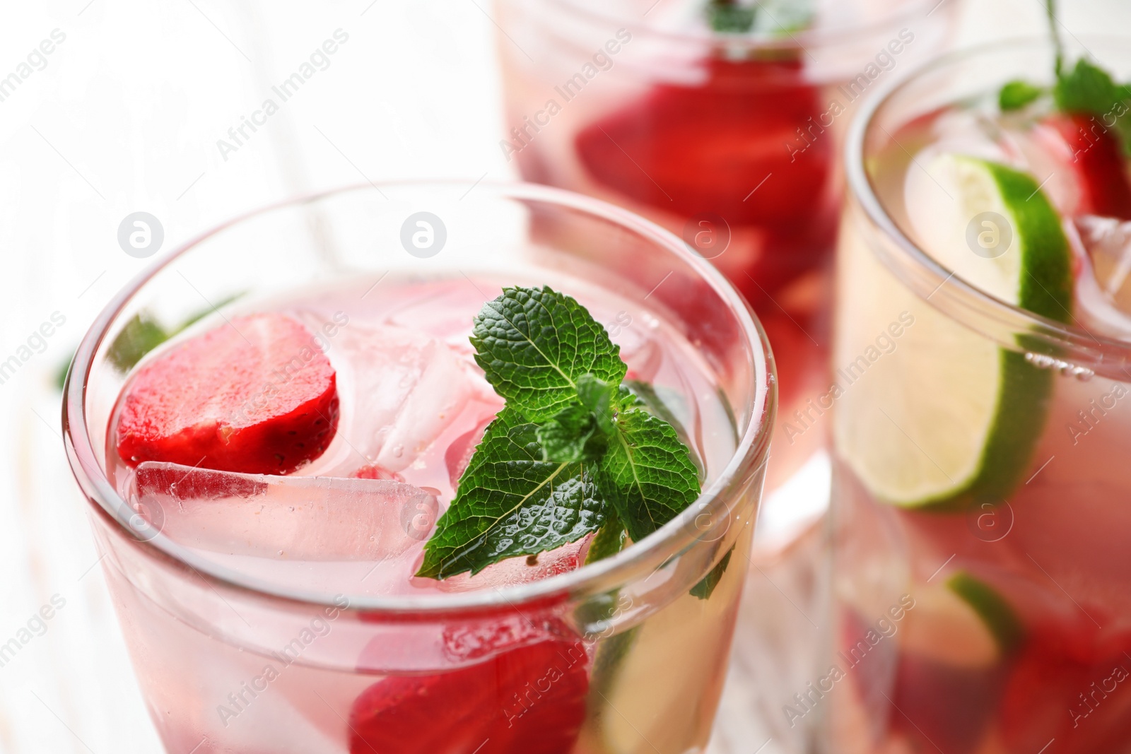 Photo of Glass of refreshing drink with strawberry, lime and mint on table, closeup view