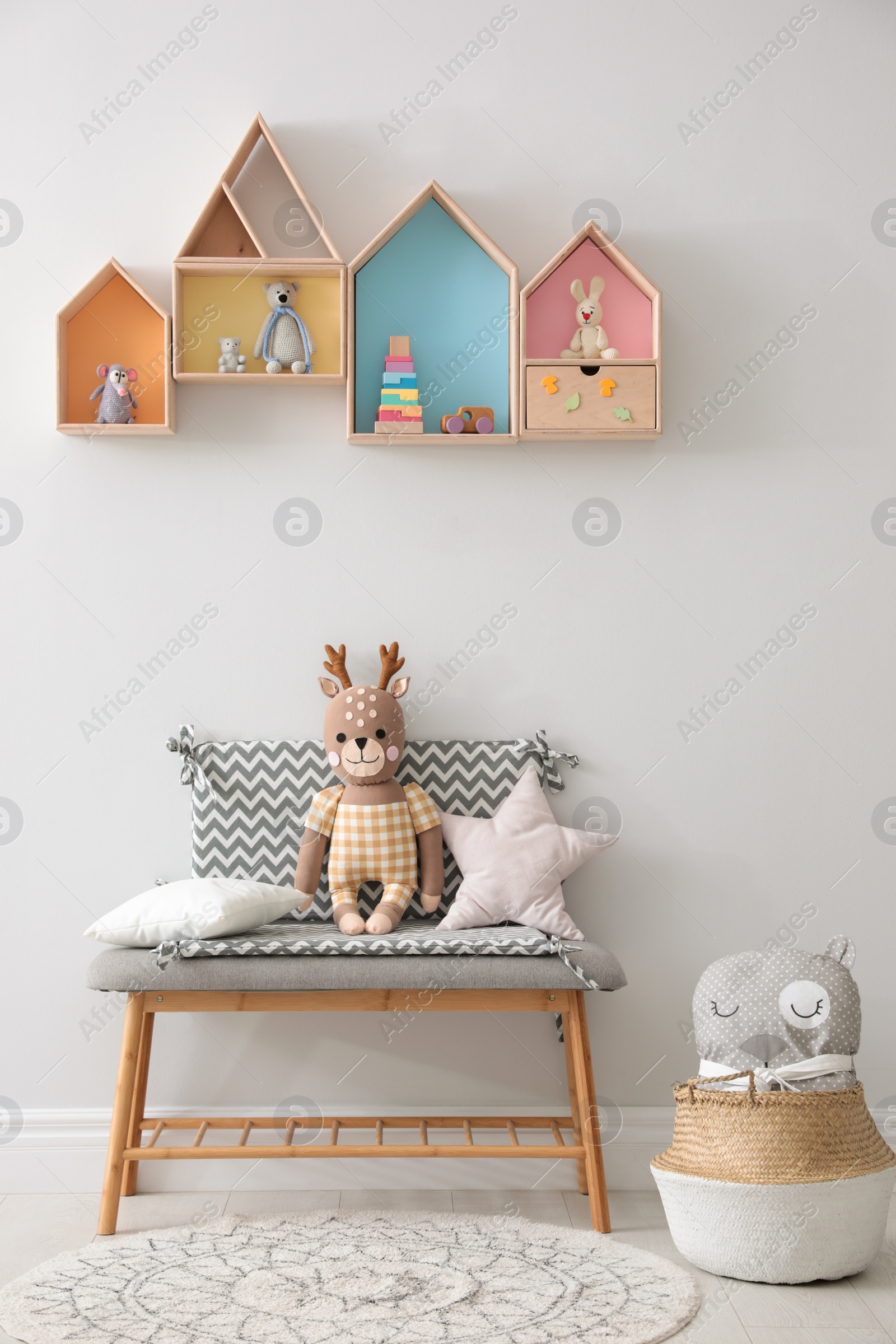 Photo of House shaped shelves and bench with toys in children's room. Interior design