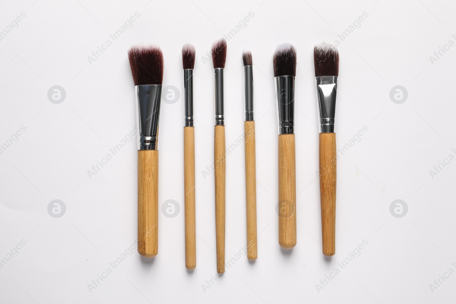 Photo of Different makeup brushes on white background, flat lay