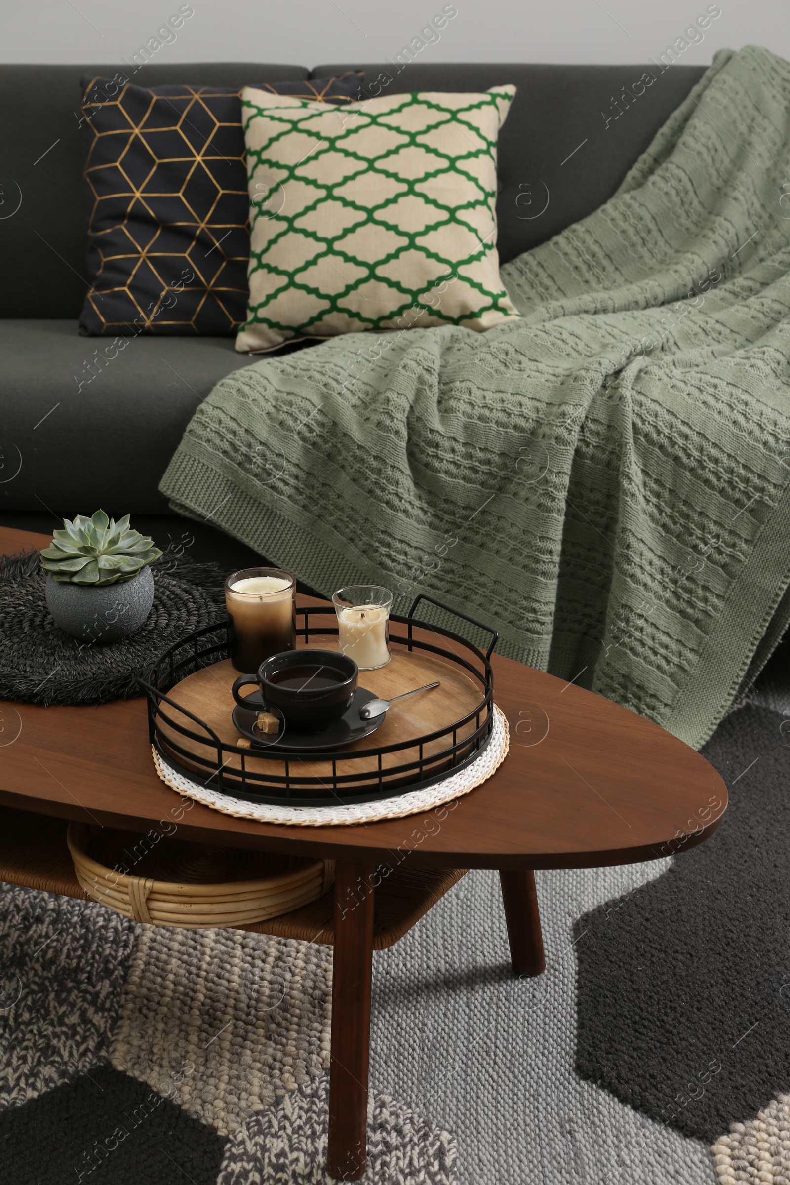 Photo of Sofa and freshly brewed coffee with decorative elements on wooden table in living room