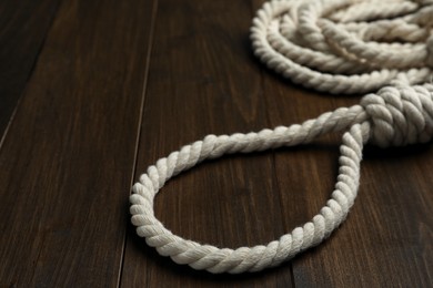 Photo of Rope noose on wooden table, closeup view