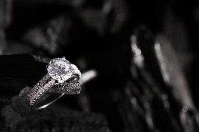 Photo of Luxury jewelry. Stylish presentation of elegant ring on coal, closeup with space for text