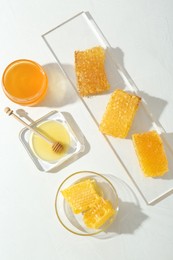 Natural honeycombs with tasty honey and dipper on white table, flat lay