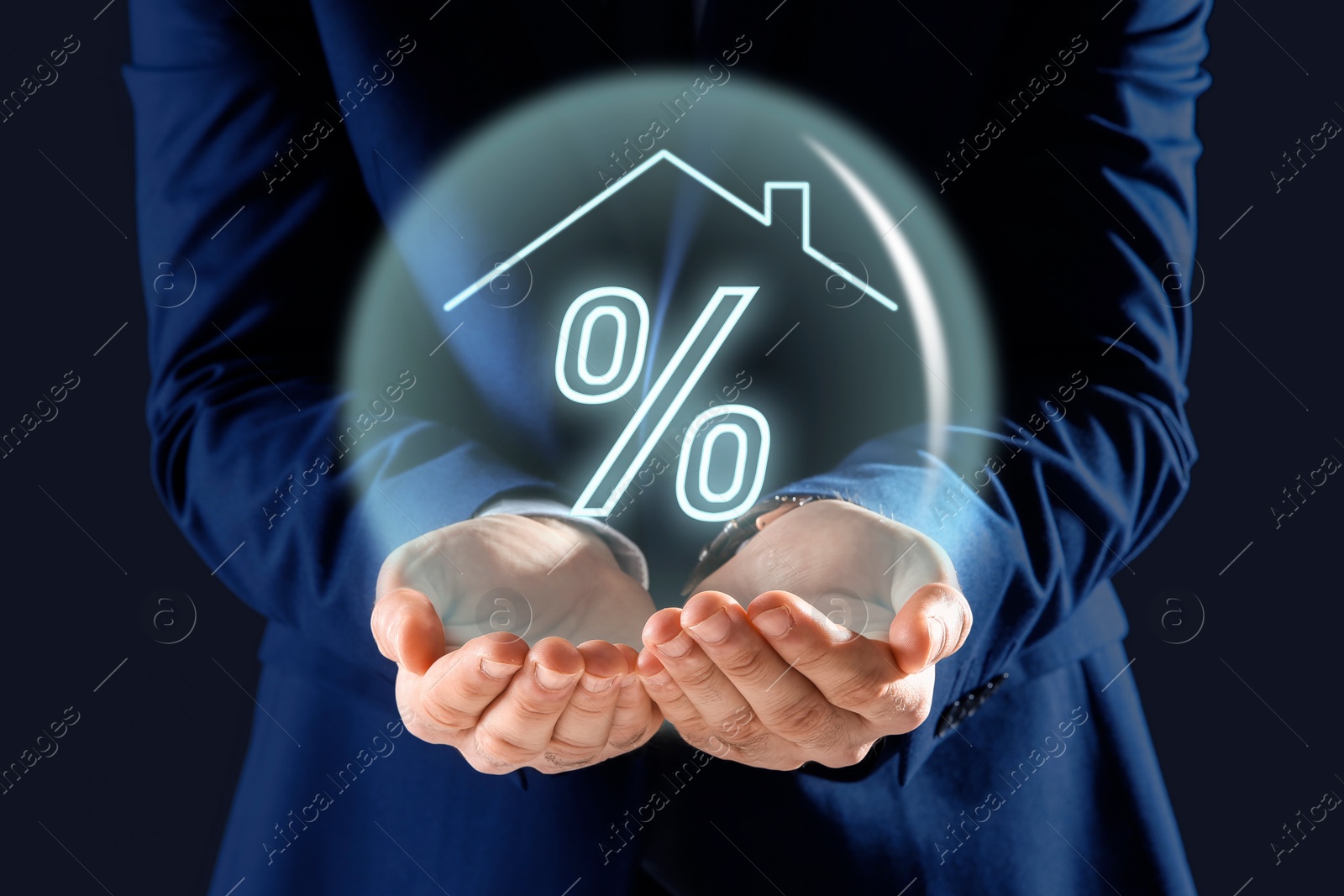 Image of Mortgage. Man holding sphere with percent sign and house roof on dark blue background, closeup