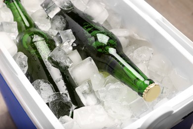 Photo of Plastic cool box with ice cubes and beer, closeup