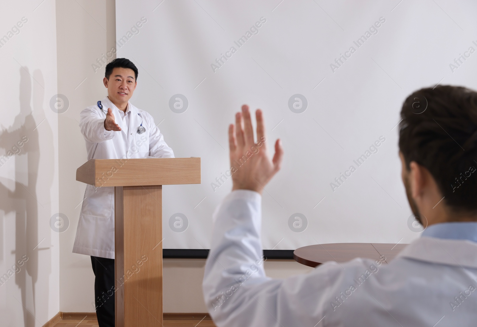 Photo of Doctor giving lecture in conference room with projection screen