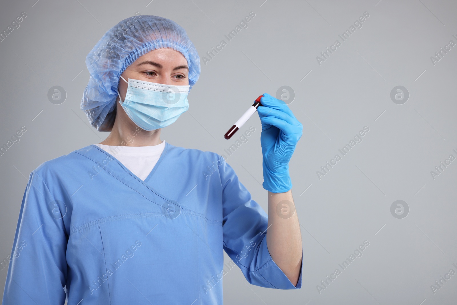 Photo of Laboratory testing. Doctor with blood sample in tube on light grey background, space for text