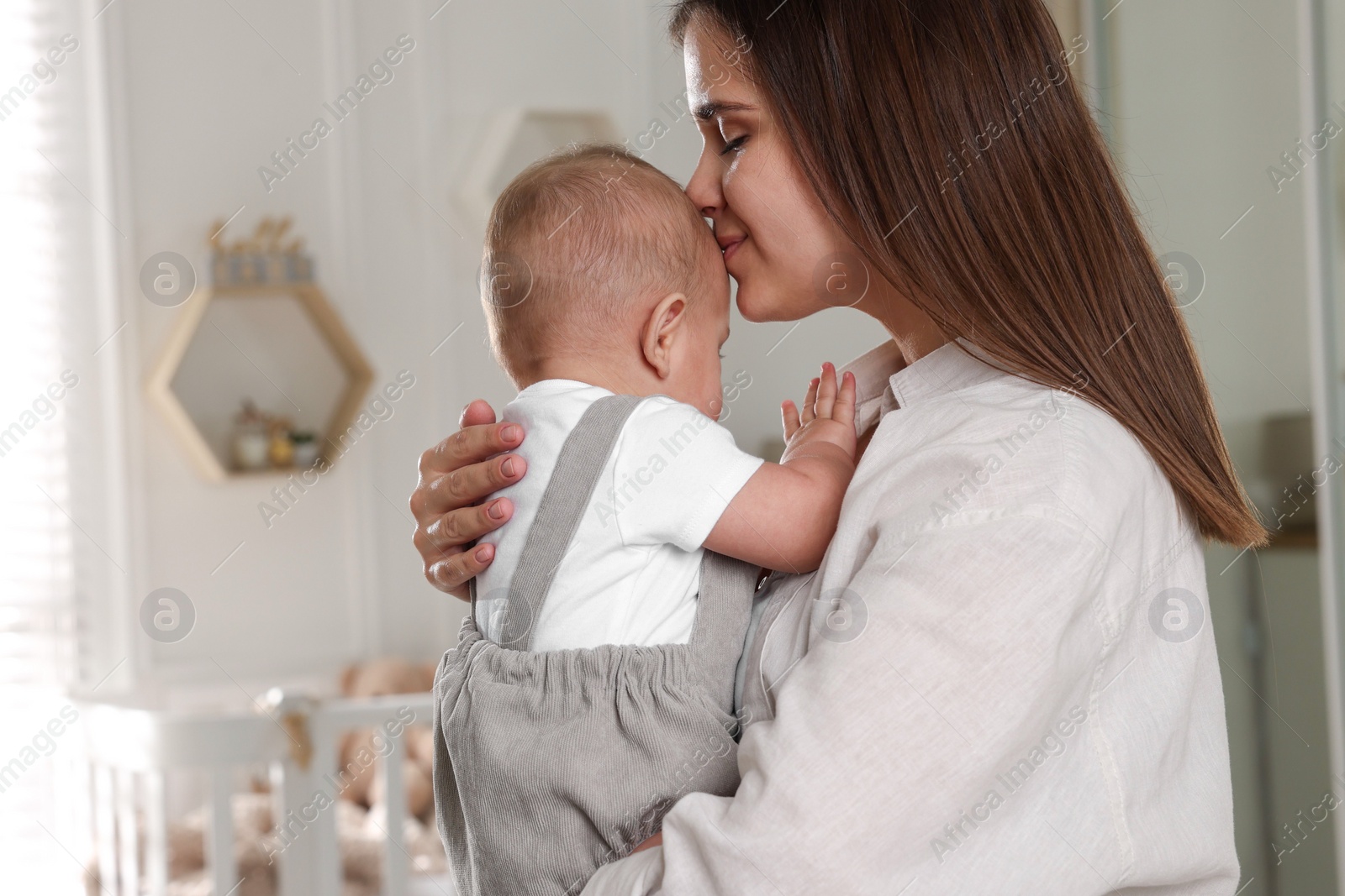 Photo of Happy young mother with her baby in nursery. Space for text