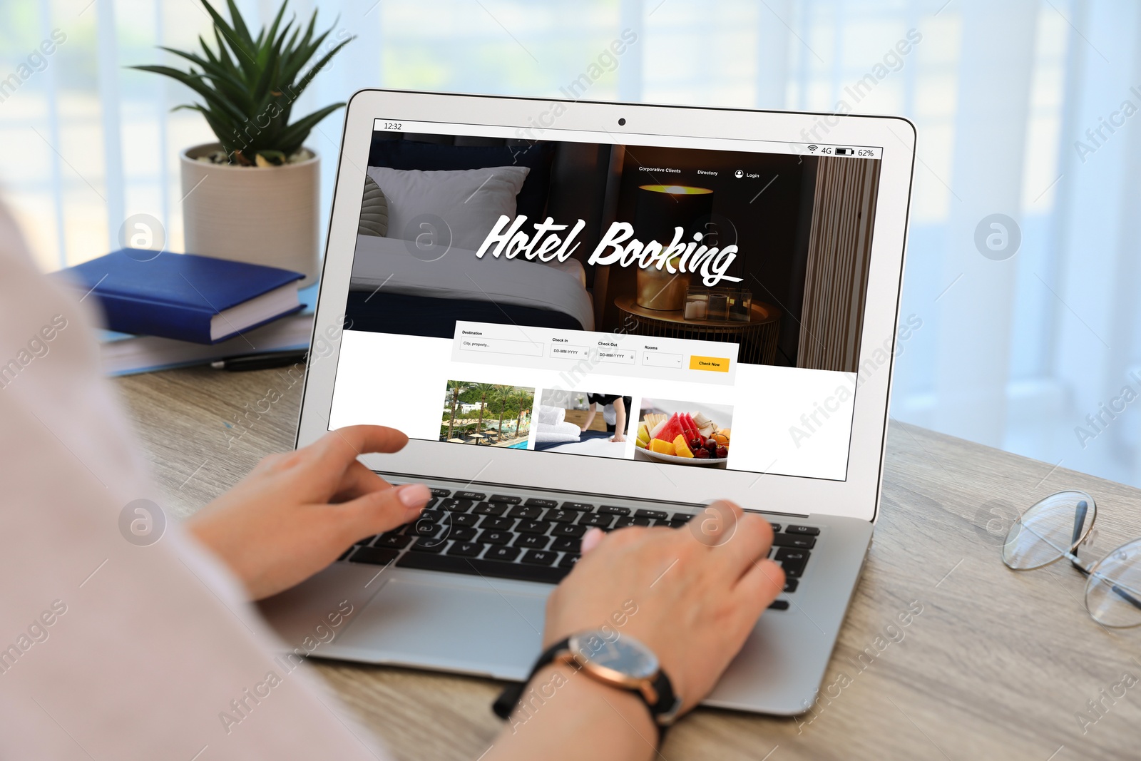 Image of Woman using laptop to book hotel at wooden table, closeup