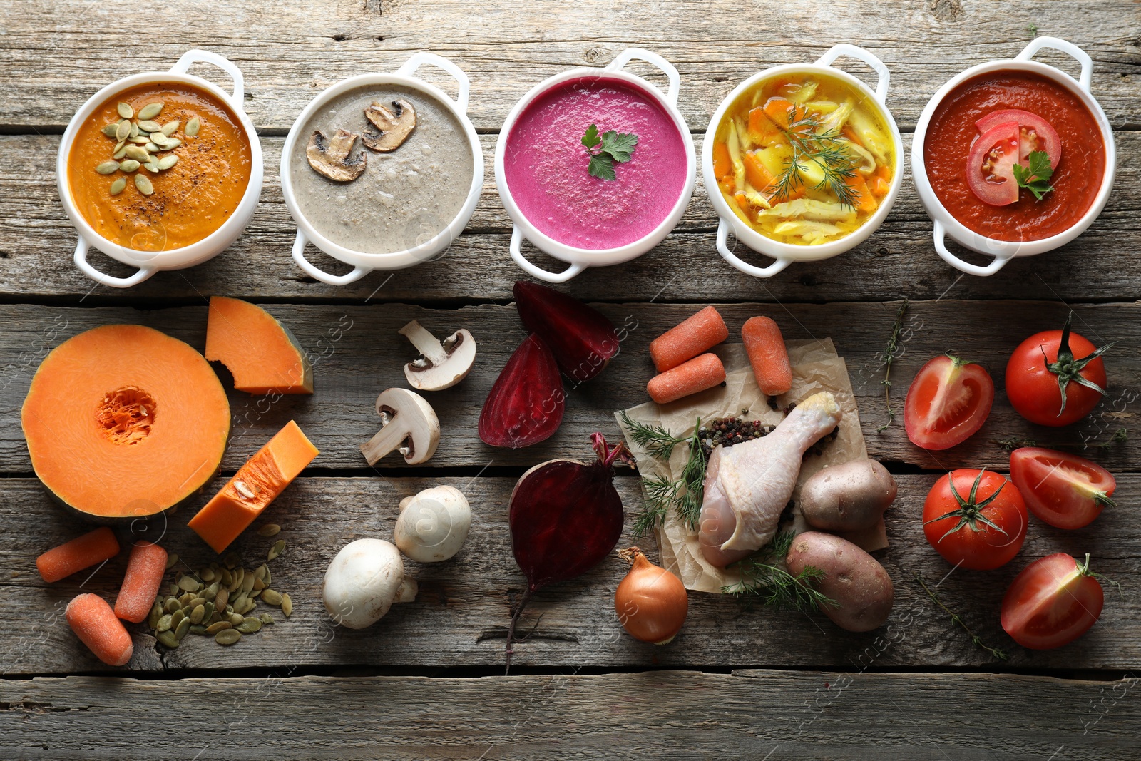 Photo of Tasty broth, different cream soups in bowls and ingredients on old wooden table, flat lay