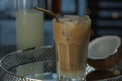 Photo of Glass of iced coffee and coconut on metal tray against blurred lights, closeup. Space for text