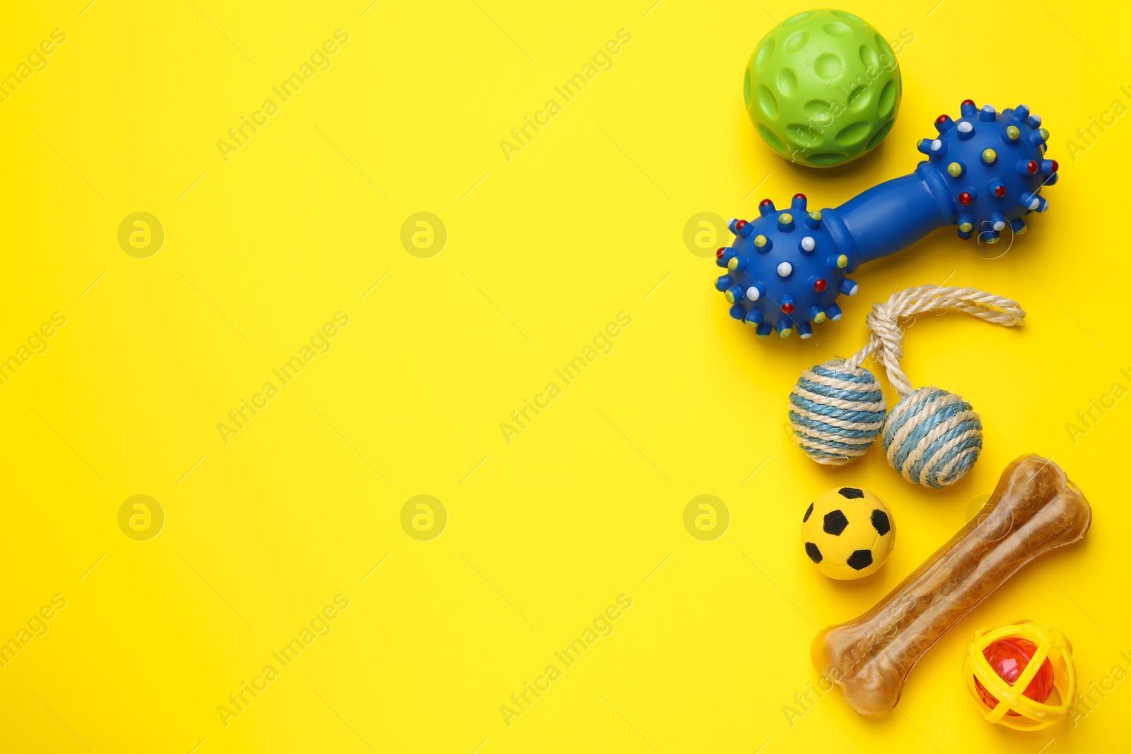 Photo of Pet toys and dog treat on yellow background, flat lay. Space for text