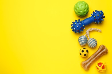 Photo of Pet toys and dog treat on yellow background, flat lay. Space for text