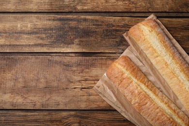 Photo of Fresh tasty baguettes on wooden table, flat lay. Space for text