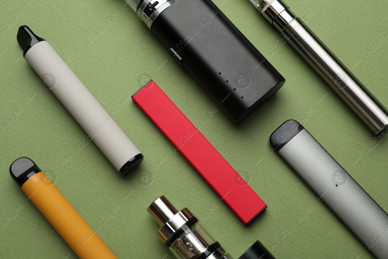 Photo of Many electronic smoking devices on olive background, flat lay