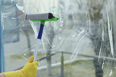 Woman cleaning window with squeegee at home, closeup. Space for text