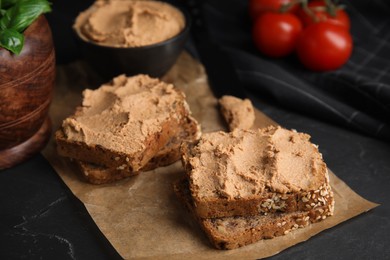 Photo of Fresh bread with delicious meat pate served on black table, closeup