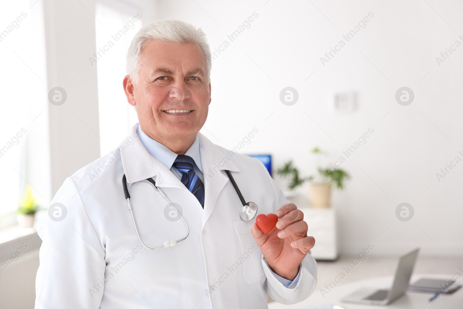 Photo of Male doctor holding small heart at workplace in clinic. Cardiology center