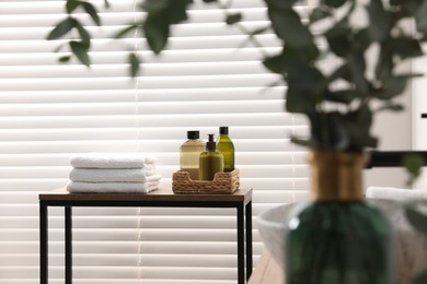 Photo of Soft towels and toiletries on wooden table in bathroom. Interior design