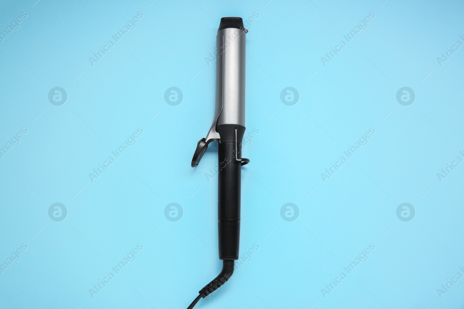 Photo of Hair styling appliance. One curling iron on light blue background, top view