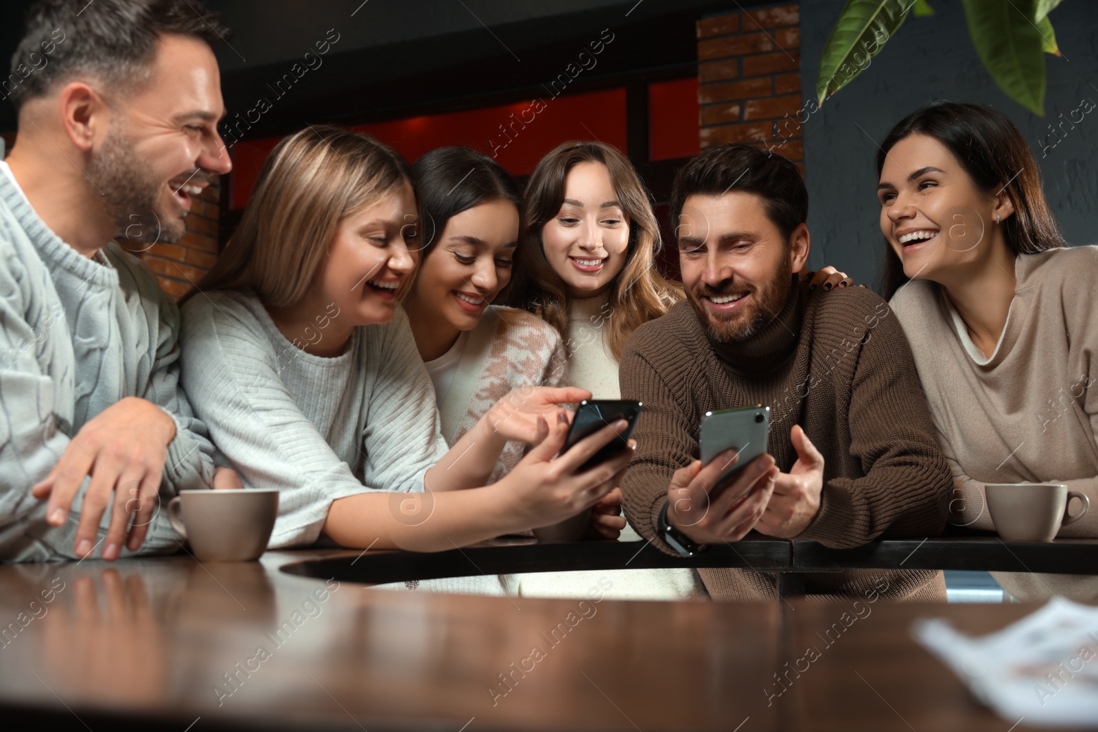 Photo of Friends with drinks and smartphones spending time together in cafe