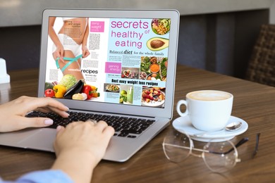 Woman reading online magazine on laptop in cafe, closeup