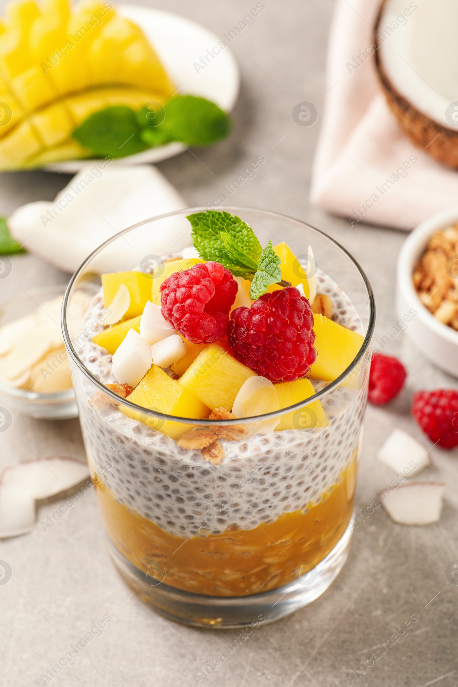 Photo of Delicious chia pudding with mango, raspberries and granola on light grey table